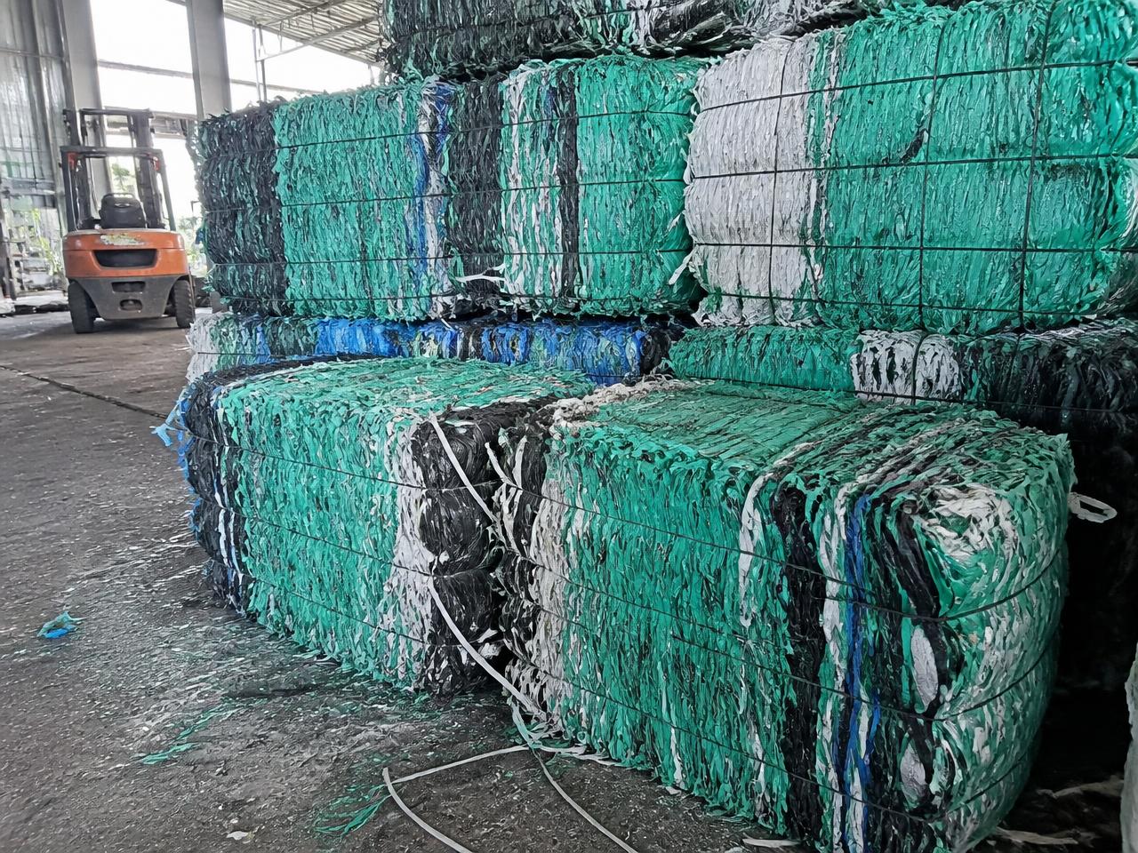 Compressed bales of PET strapping waste stacked in a recycling warehouse for container loading